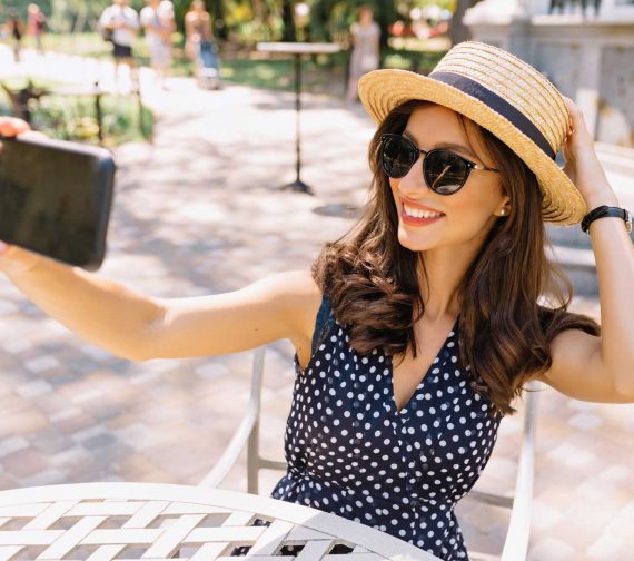 style-beautiful-woman-with-short-dark-hair-charming-smile-is-sitting-summer-cafeteria-sunlight-she-is-wearing-summer-hat-sunglasses-making-selfie.jpg